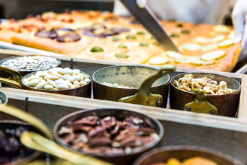Cutting foccacia bread with knife, nuts, spices in containers and toppings baked in oven, chef in restaurant kitchen