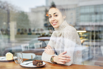 young smiling woman sits in cafe