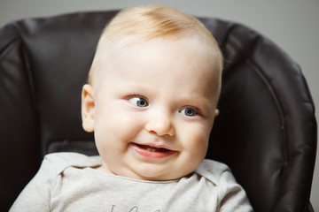 Baby in highchair with interested look and broad smile