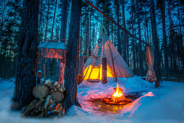 Yurt in the forest. A dwelling in a forest with a fire. The wigwam in the snow-covered forest. Ethnography. Forest dwelling. © Grispb