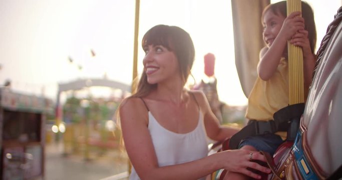 Mother and daughter having fun on carousel ride at funfair
