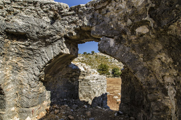 Ruins of the ancient city of Sidima, Turkey, a wall with a partially preserved arch against a blue...