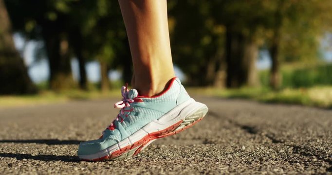 feet and legs girl jogging and running in a street with trees and nature, for music and run slow in sunset. concept of happiness for sports and fitness relaxation in nature.passion for sport