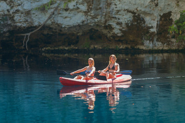 Fototapeta na wymiar two girls kayaking on a blue lake, Laguna Dudu
