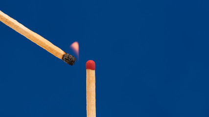 Matchstick Set Fire to Another One with Blue Background .