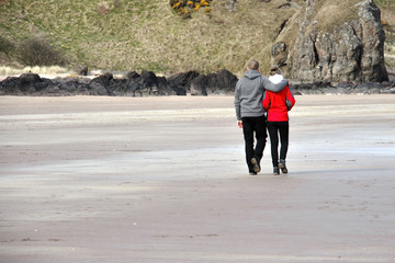 Couple is walking at the beach. St Cyrus, Aberdeenshire, Scotland, UK. 
