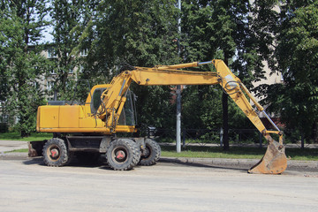 yellow excavator with a large bucket on the street