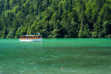 Sightseeing boat on green water against green forest. Königssee lake, Germany	