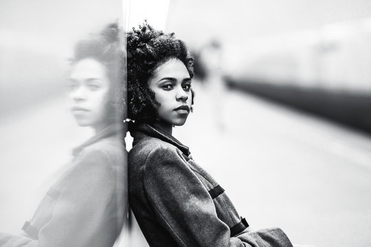 Black And White Portrait Of Charming African American Female In The Coat Leaning Against A Mirror Wall; The Greyscale Shot Of A Cute Black Teenage Girl Sitting On The Bench Of An Underground Station