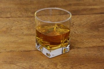 a glass of whiskey on a wooden table top