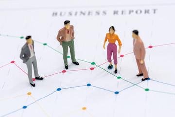 Mini people figures standing on business graphs