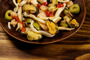 Seafood salad with shrimp, squid and mussels on wooden table