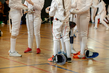 Girls, participants in fencing competitions on swords stand in the center of fencing hall waiting...