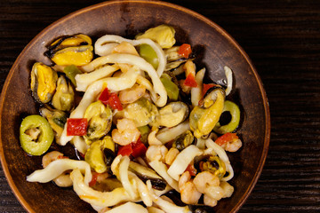 Seafood salad with shrimp, squid and mussels on wooden table