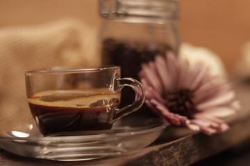 Portrait of a cup of coffee on a wooden board, with a flower and a container of coffee beans. Concept: Relax, breakfast, love