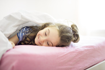 Obraz premium Portrait of a girl under covers by white sheet