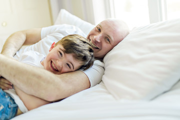 Obraz na płótnie Canvas Happy father and son having fun together on a bed