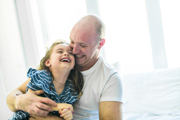 Happy father and daughter having fun together on a bed