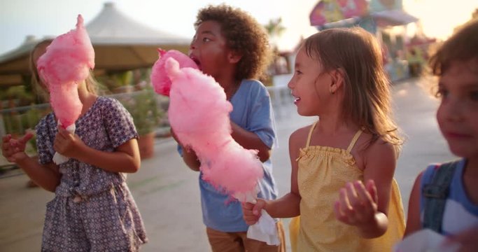 Multi-ethnic children eating cotton candy and pop-corn at amusement park