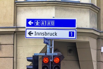 A traffic light with arrows and an exit sign for 1 and 10 highways in the direction of Innsbruck....