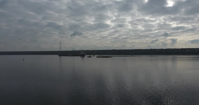 Dry cargo ship and pusher on the fork of a calm river. Summer day. Camera moves in the air near from the ship. Aerial view.