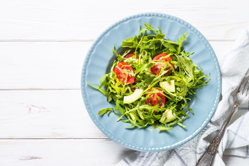 Healthy vegan salad from arugula, avocado and tomatoes.