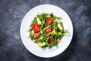 Healthy vegan salad from arugula, avocado and tomatoes.
