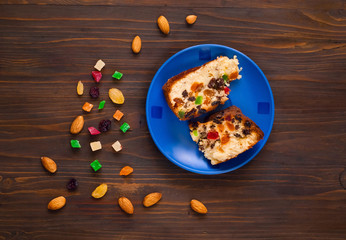 Pieces of homemade muffins with raisins, candied fruits and almonds on a blue plate on a wooden background.