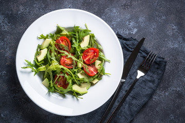 Green salad from arugula, avocado and tomatoes.