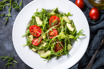 Healthy vegan salad from arugula, avocado and tomatoes.