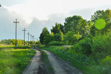Fototapeta na wymiar Country road beyond the forest and power line. Summer rural landscape.