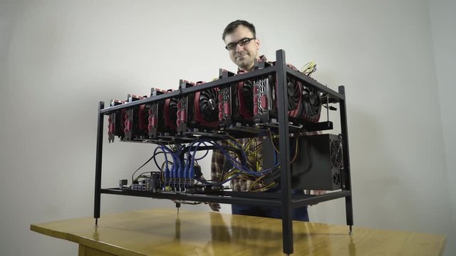 Future with a lot of money without doing anything. All happy young smiling man hugging his mining rig machine with powerful graphics cardS, concept cryptocurrency computer, symbolic shot.