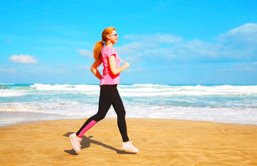 Fitness young woman is running summer along the beach near the sea at summer day