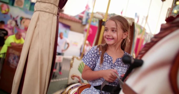 Young girl riding a carousel horse on a merry-go-round ride