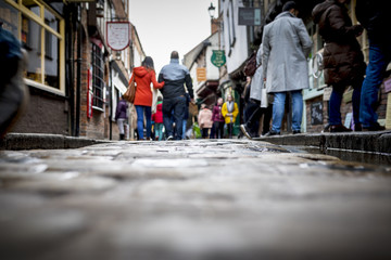 Low down shot of people and couple walking holding hands down a old traditional cobbled English...