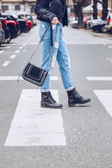 fashion blogger outfit details. fashionable woman wearing ripped vintage denim jeans, suede jacket, black biker boots -ankle shoes and black trendy handbag. detail of a perfect fall fashion outfit. 