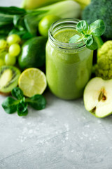 Glass jar mugs with green health smoothie, kale leaves, lime, apple, kiwi, grapes, banana, avocado, lettuce. Copy space. Raw, vegan, vegetarian, alkaline food concept. Banner