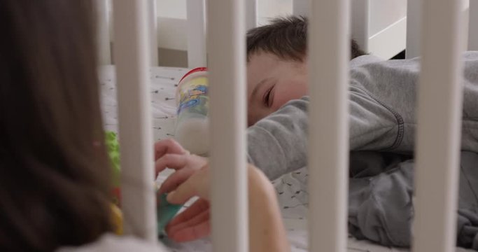 Toddler playing with toys in crib and laughs