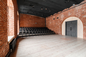 Loft style. Hall with black chairs for webinars and conferences. A huge room with large Windows,...