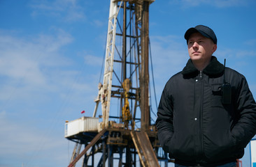 Security guard with walkie talkie, controlling outdoor oil drilling rig station platform. Safety...