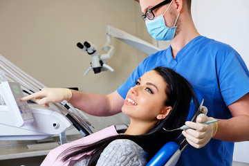 A dentist hands working on young woman patient with dental tools.