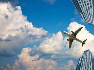 Fototapeta na wymiar airliner in sky on skyscrapers background