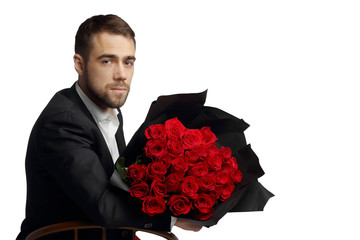Portrait of a young man dressed in business style with a large bouquet of red roses.