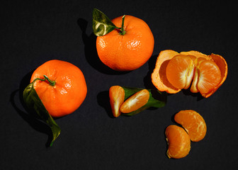 Juicy mandarin, tangerine or orange, with pieces lobules and segments on pure black background...