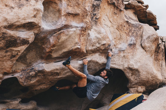 Man Bouldering outside with a heel hook