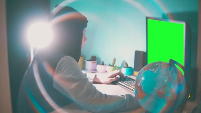 Hacker man programmer in the hood using computer for hack information and data from user account. green key teal orange color grading indoors online web social media