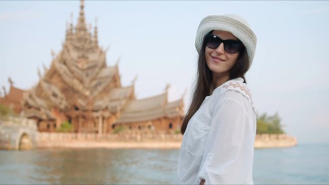 Young woman touirist smiling and posing in front of the ancient temple. Happy vacation concept