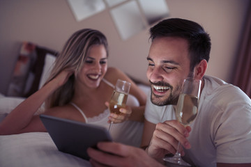 Couple using tablet in bedroom