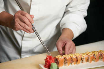 Male chef cooks preparing sushi in the restaurant kitchen. Chef cooking Classic Japanese sushi, served on a stone plate