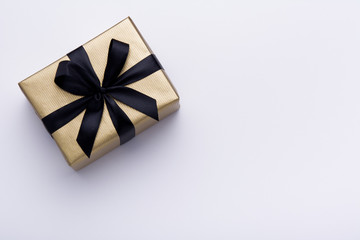 Hands holding wrapped gift box with colored ribbon as a present for Christmas, new year, mother's day, anniversary, birthday, party,  on white background, top view. Present for a colleague at work.